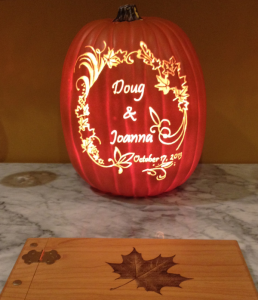 A tall pumpkin is the new couple's name carved into a pumpkin framed by ornate scroll work.