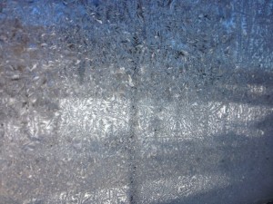 In Photo. Looking through a window the outside scene is obscured by dazzling patterns of frost. End photo.