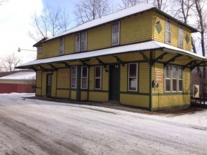 In photo. An old train station for which "Depot Hill Road" is named. The old structure is recognizable as a train station due to its characteristic architechual design. It is currently used as the county municipal building which is open for business only on Thursdays from 8AM to 5PM. End photo.