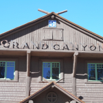 In photo. A rustic looking building with a conventional roof line and double hung window. Across the front of the building above the second floor are the words "Grand Canyon." This is the visitors center near the southern rim. End photo.