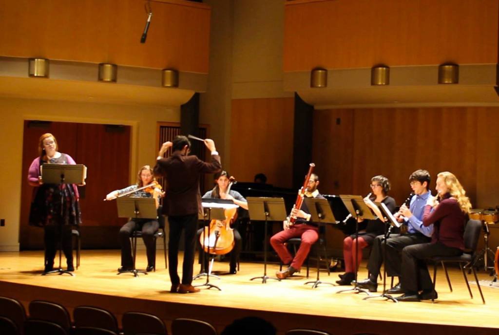 In photo. William is seen here in front of a chamber orchestra. His back is to the camera and he is conducting a performance of one of his pieces. End photo.