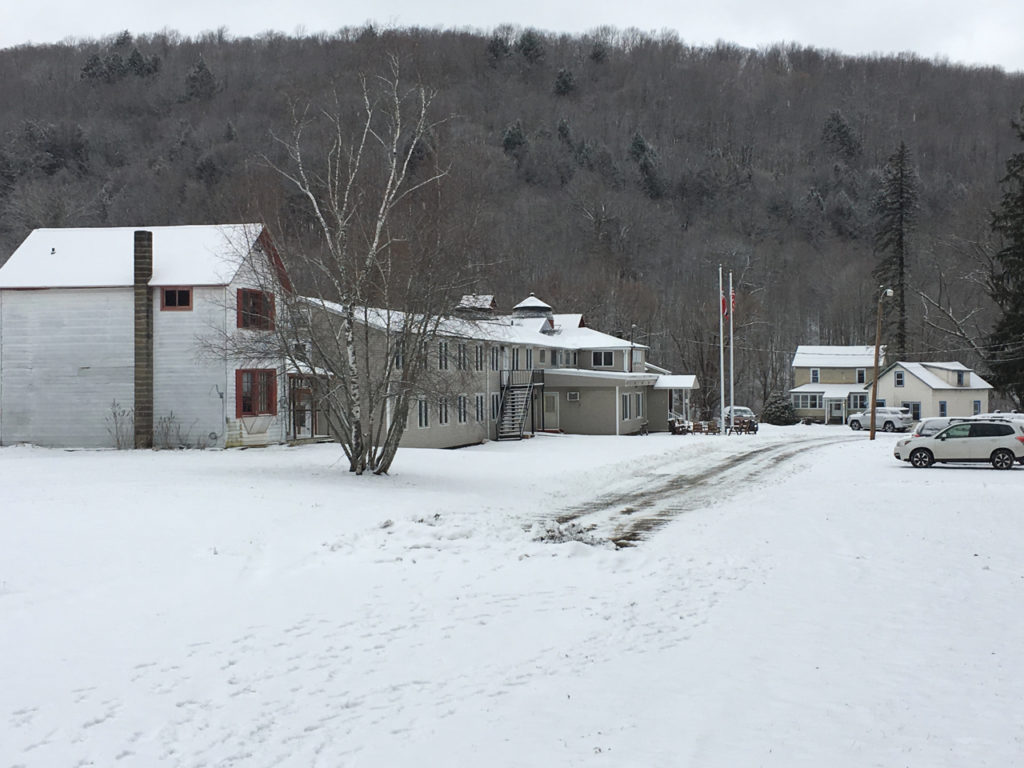 In photo -- The LOV lodge, the front walk and road are seen from the base of the logging road. There is plenty of fresh snow and the road in front of the lodge has been freshly plowed. Out of photo.