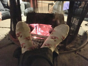 In photo -- Warming stocking clad feet by the fire. The feet form a "V" and the well stoked fire is seen between the angle of the feet. Out of photo.