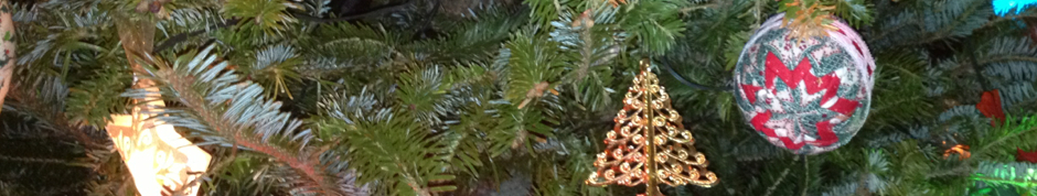 In photo. The very narrow slice of imagery is a Christmas tree branch on which are hung a gilded ornament and fabric quilted tree ball. End photo.