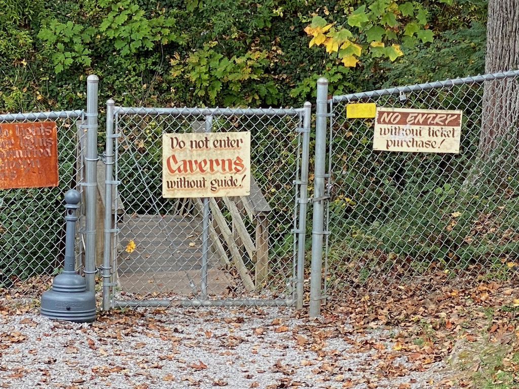 IN PHOTO. A simple chain link fence with a warning sign is all the separates the general public from the sheer terror, ah, rather, the awesome underground wonders of the caverns. OUT OF PHOTO.